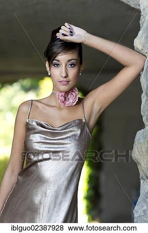 "Young woman with an updo hairstyle, silvery evening gown, posing in front of a stone wall" View Large Photo Image Stock Photo - "Young woman with an updo hairstyle, silvery evening gown, posing in front of a stone wall". Fotosearch
