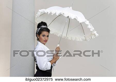 "Young woman with an updo hairstyle, wearing a white shirt and holding a white umbrella" View Large Photo Image Stock Photography - "Young woman with an updo hairstyle, wearing a white shirt and holding a white umbrella". Fotosearch