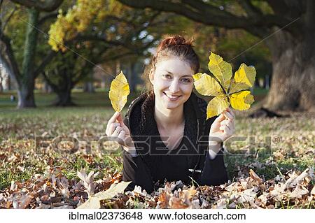 Young woman with autumn leaves in her hands on a meadow View Large Photo Image Stock Photo - Young woman with autumn leaves in her hands on a meadow. Fotosearch