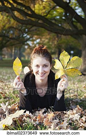 Young woman with autumn leaves in her hands on a meadow View Large Photo Image Stock Photo - Young woman with autumn leaves in her hands on a meadow. Fotosearch