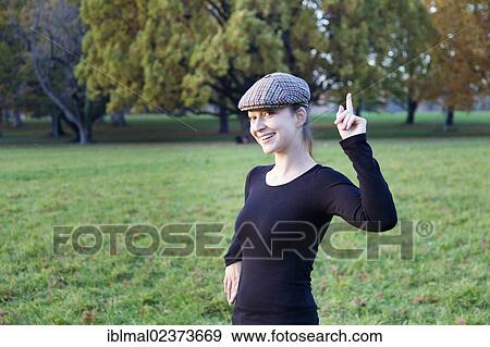 Stock Photo - Young woman with cap and pointing index finger. Fotosearch