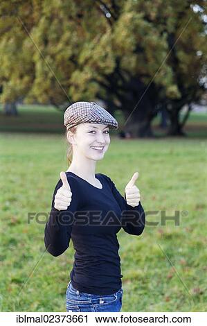 Stock Image - "Young woman with cap, two thumbs up". Fotosearch