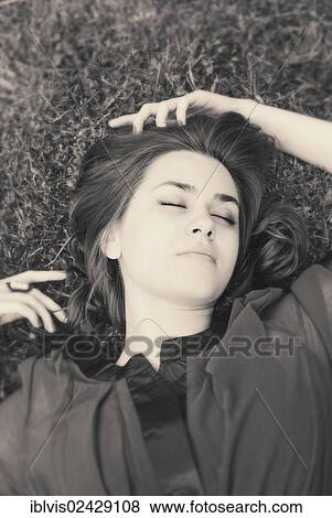 Young woman with closed eyes lying on grass View Large Photo Image Stock Photo - Young woman with closed eyes lying on grass. Fotosearch