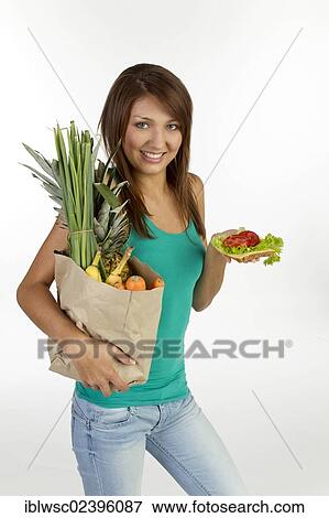 Young woman with grain bread topped with cheese and tomato and a bag of fruit and vegetables View Large Photo Image Stock Photo - Young woman with grain bread topped with cheese and tomato and a bag of fruit and vegetables. Fotosearch