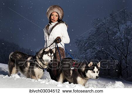 Stock Image - "Young woman with huskies in the snow, Kolsassberg, Innsbruck-Stadt District, North Tyrol, Tyrol, Austria, Europe". Fotosearch