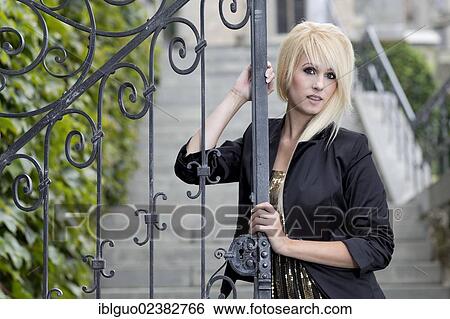 Young woman with long blond hair posing at an entrance gate View Large Photo Image Stock Photograph - Young woman with long blond hair posing at an entrance gate. Fotosearch