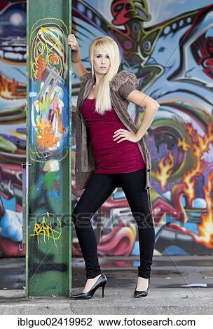 Young woman with long blonde hair posing against a steel girder in front of a wall with graffiti View Large Photo Image Stock Image - Young woman with long blonde hair posing against a steel girder in front of a wall with graffiti. Fotosearch