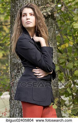 Young woman with long hair wearing a black blazer in front of a tree View Large Photo Image Picture - Young woman with long hair wearing a black blazer in front of a tree. Fotosearch