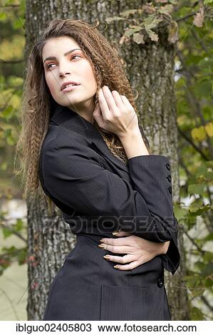 Young woman with long hair wearing a black blazer in front of a tree View Large Photo Image Stock Image - Young woman with long hair wearing a black blazer in front of a tree. Fotosearch