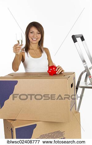 "Young woman with moving boxes, a piggy bank and a glass of champagne in her hand" View Large Photo Image Stock Photo - "Young woman with moving boxes, a piggy bank and a glass of champagne in her hand". Fotosearch