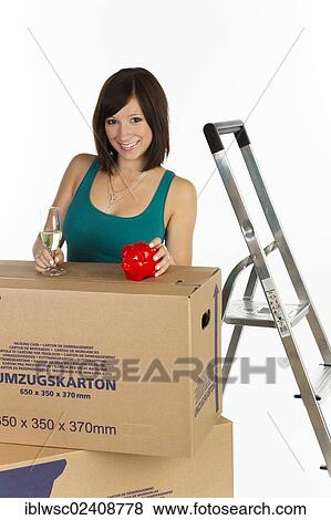 "Young woman with moving boxes, a piggy bank and a glass of champagne in her hand" View Large Photo Image Stock Photo - "Young woman with moving boxes, a piggy bank and a glass of champagne in her hand". Fotosearch