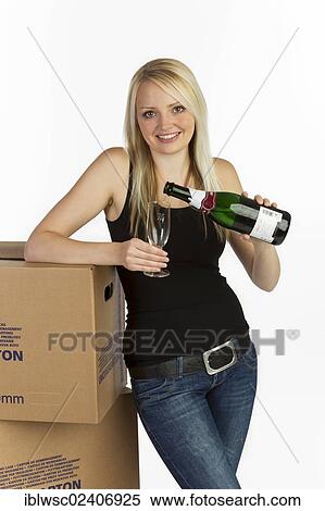 Stock Photography - "Young woman with moving boxes, bottle and glass of champagne". Fotosearch