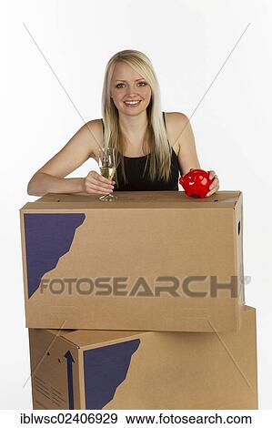 "Young woman with moving boxes, glass of champagne and piggy bank" View Large Photo Image Stock Photo - "Young woman with moving boxes, glass of champagne and piggy bank". Fotosearch