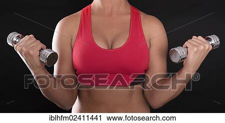 Young woman's upper body wearing a red sports bra while doing fitness training with chrome dumbbells View Large Photo Image Stock Image - Young woman's upper body wearing a red sports bra while doing fitness training with chrome dumbbells. Fotosearch