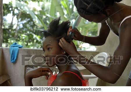Stock Image - "Young women braiding their hair, Tchawa, Leogane, Haiti, North America". Fotosearch