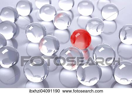 Stock Image - A red glass ball amidst many colourless glass balls. Fotosearch