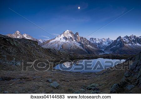 Stock Image - Aiguille Verte mountain, reflected in the Lac des Chesery after sunset, Chamonix, Rhone-Alpes, France, Europe. Fotosearch