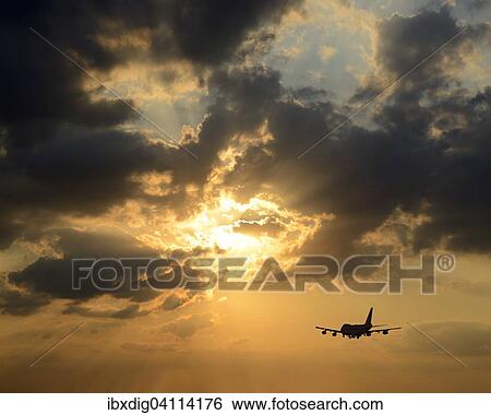 Stock Photograph - Airplane, airliner, silhouette against sunset with dramatic clouds. Fotosearch