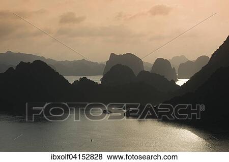 Boat on the water at sunset in the Ha Long Bay or Vinh Ha Long, limestone cliffs, UNESCO World Heritage Site, Gulf of Tonkin, North Vietnam, Vietnam, Asia View Large Photo Image Stock Photo - Boat on the water at sunset in the Ha Long Bay or Vinh Ha Long, limestone cliffs, UNESCO World Heritage Site, Gulf of Tonkin, North Vietnam, Vietnam, Asia. Fotosearch