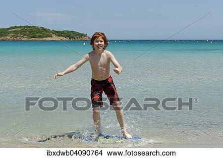 Boy surfing with his boogie board, beach board or skimboard on the beach, bay of Rondinara, southeast coast, Corsica, France, Europe View Large Photo Image Picture - Boy surfing with his boogie board, beach board or skimboard on the beach, bay of Rondinara, southeast coast, Corsica, France, Europe. Fotosearch