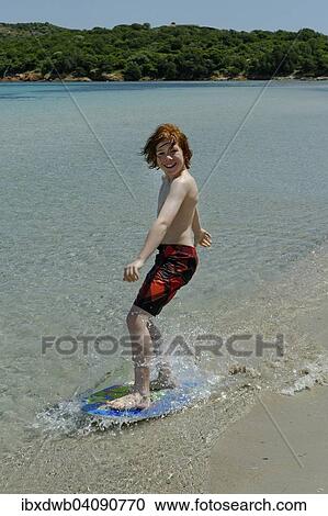 Boy surfing with his boogie board, beach board or skimboard on the beach, bay of Rondinara, southeast coast, Corsica, France, Europe View Large Photo Image Stock Image - Boy surfing with his boogie board, beach board or skimboard on the beach, bay of Rondinara, southeast coast, Corsica, France, Europe. Fotosearch