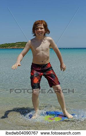 Boy surfing with his boogie board, beach board or skimboard on the beach, bay of Rondinara, southeast coast, Corsica, France, Europe View Large Photo Image Stock Photo - Boy surfing with his boogie board, beach board or skimboard on the beach, bay of Rondinara, southeast coast, Corsica, France, Europe. Fotosearch