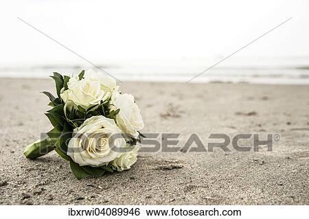 Stock Photograph - Bridal bouquet of white roses lying on a North Sea beach. Fotosearch