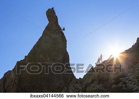 Stock Photograph - Climber abseiling off rocky pinnacle, Chamonix, Rhone-Alpes, France, Europe. Fotosearch