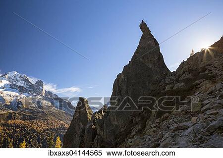 Stock Photography - Climber standing on rocky pinnacle overlooking the mountains of Chamonix, Chamonix, Rhone-Alpes, France, Europe. Fotosearch