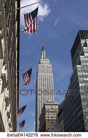 Stock Photo - Empire State Building, US flags on a building, Manhattan, New York, USA. Fotosearch