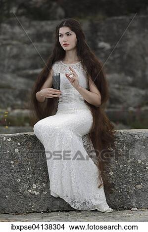 Picture - Enactment of the painting The Damsel of the Sanct Grael, The Damsel of the Holy Grail by Dante Gabriel Rossetti, young woman in a white dress with a chalice. Fotosearch