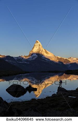 Stock Photography - First sunlight on the Matterhorn, with reflection in Stellisee lake, with a person, Zermatt, Canton of Valais, Switzerland, Europe. Fotosearch