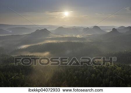 Stock Image - Fog at sunrise, morning atmosphere in the Elbe Sandstone Mountains, Saxon Switzerland, Saxony, Germany, Europe. Fotosearch