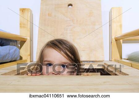 Stock Image - Girl, 3 years, looking through a hatch. Fotosearch