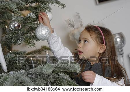 Picture - Girl decorating a Christmas tree with baubles, Bavaria, Germany, Europe. Fotosearch