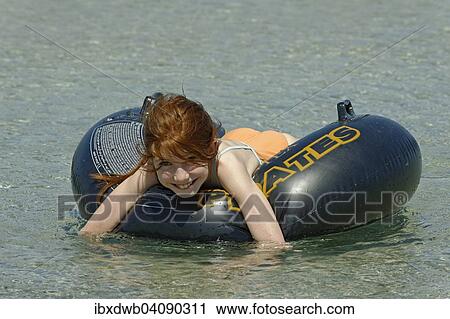 Girl in a big floating tyre in the turquoise waters in the Bay of Rondinara, southeast coast, Corsica, France, Europe View Large Photo Image Stock Image - Girl in a big floating tyre in the turquoise waters in the Bay of Rondinara, southeast coast, Corsica, France, Europe. Fotosearch
