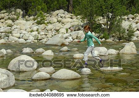 Stock Photography - Girl jumping over rocks in the river Solenzara, Corse-du-Sud, Corsica, France, Europe. Fotosearch