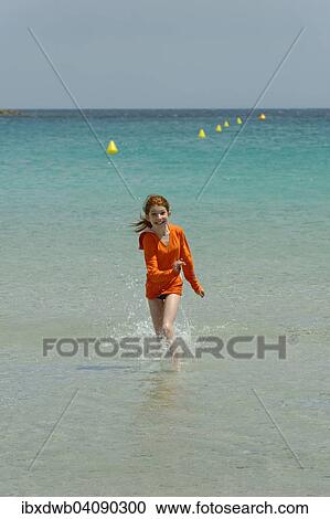 Stock Image - Girl running through the turquoise waters of the Bay of Rondinara, southeast coast, Corsica, France, Europe. Fotosearch