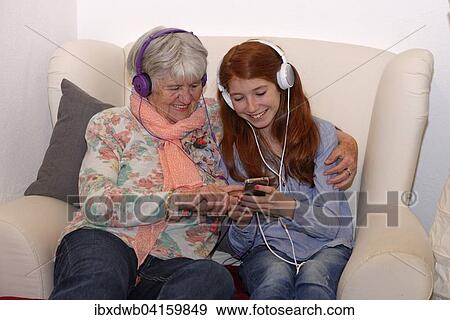Granddaughter and grandmother listening to music through headphones, digital music, Bavaria, Germany, Europe View Large Photo Image Stock Photo - Granddaughter and grandmother listening to music through headphones, digital music, Bavaria, Germany, Europe. Fotosearch