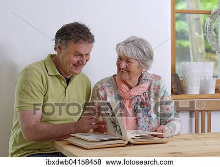 Stock Photo - Grown-up son and elderly mother looking at a photo album, Bavaria, Germany, Europe. Fotosearch