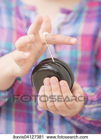 Hands of a girl, 5 years, holding black wooden yo-yo View Large Photo Image Stock Image - Hands of a girl, 5 years, holding black wooden yo-yo. Fotosearch