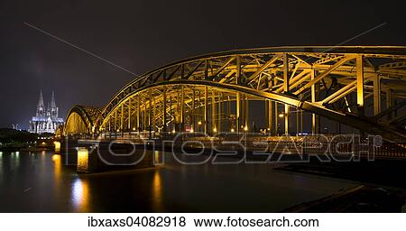 Stock Photo - Hohenzollern Bridge, illuminated at night, Cologne Cathedral behind, Cologne, North Rhine-Westphalia, Germany, Europe. Fotosearch