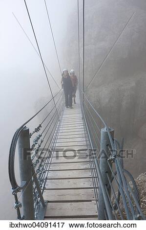 Stock Photo - Lagazuoi Via Ferrata, Kaiserjagerweg trail, climbers on the suspension bridge, fog, Falzarego Pass, Cortina d'Ampezzo, Veneto, Italy, Europe. Fotosearch