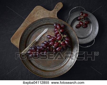 Pewter plates with grapes on a black underground View Large Photo Image Stock Photography - Pewter plates with grapes on a black underground. Fotosearch