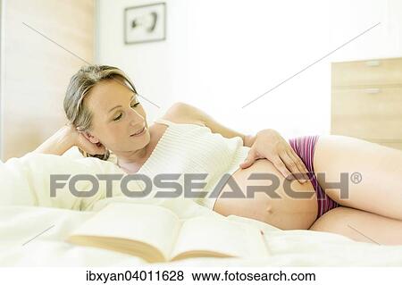 Stock Photo - Pregnant woman lying in bed. Fotosearch