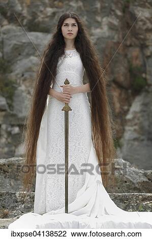 Stock Image - Reminiscence to Joan of Arc, Jeanne d'Arc, young woman in a white dress with a sword. Fotosearch