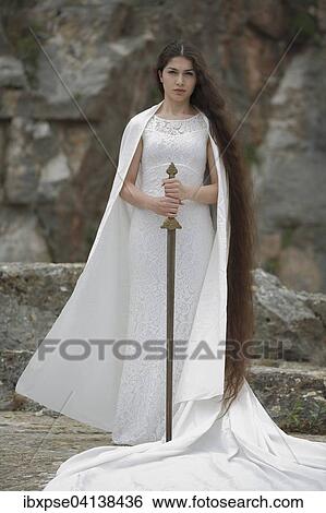 Stock Photograph - Reminiscence to Joan of Arc, Jeanne d'Arc, young woman in a white dress with a sword. Fotosearch