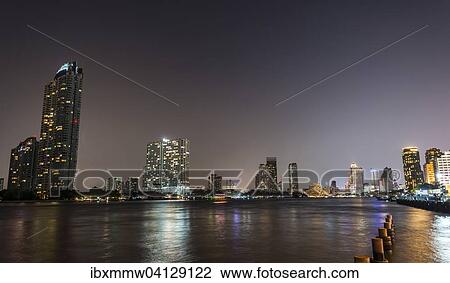 Stock Image - River promenade in the evening with a Ferris wheel and the skyline on the river Mae Nam Chao Phraya, Asiatique, Bangkok, Thailand, Asia. Fotosearch