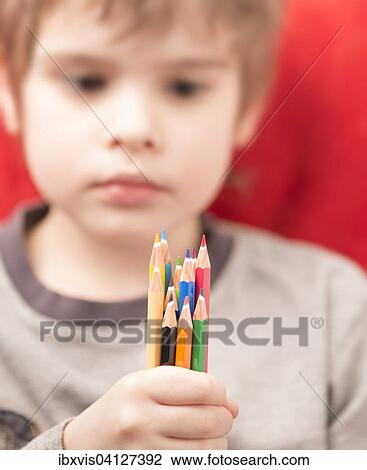 Serious looking girl holding coloured pencils in her hand View Large Photo Image Stock Image - Serious looking girl holding coloured pencils in her hand. Fotosearch