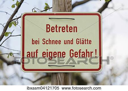 Stock Photography - Sign in German, saying entering in snowy and icy conditions at your own risk. Fotosearch